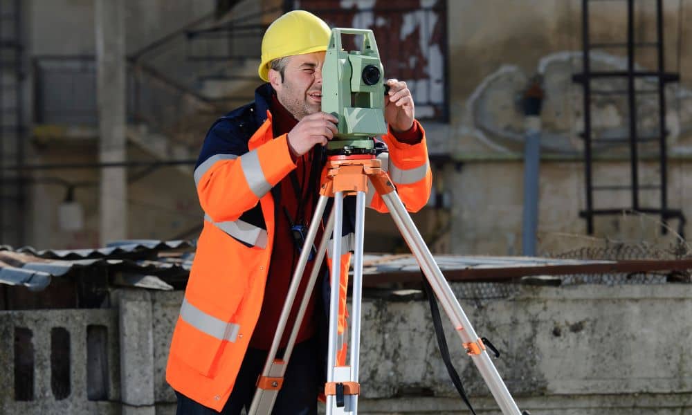 Land surveyor using tripod equipment at a redevelopment site during an ALTA title survey.
