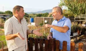 Two neighbors arguing over a backyard fence showing the need for an alta title survey