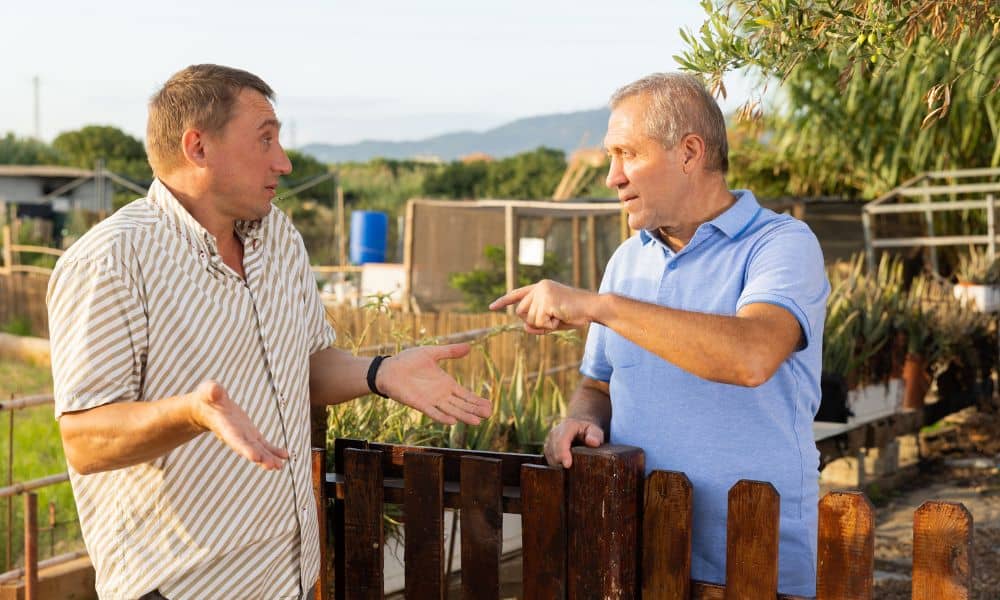 Two neighbors arguing over a backyard fence showing the need for an alta title survey