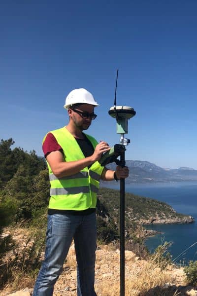 Surveyor using GPS equipment near waterfront showing how environmental treatments can affect an ALTA Land Title Survey
