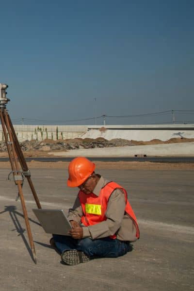 Alta title survey data updates - ALTA SURVEY Idaho Land surveyor using a laptop beside survey equipment on a road site illustrating how professionals keep alta title survey data accurate during public project delays