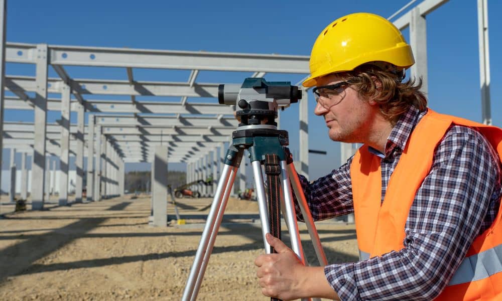 Construction site land surveyor - ALTA SURVEY Idaho Surveyor using a level instrument at a construction site before building begins