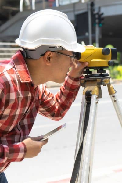 Licensed land surveyor using a total station instrument while conducting measurements for an ALTA Survey during site evaluation