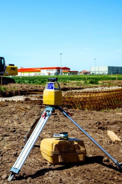 Survey equipment measuring property boundaries during an alta title survey to check site conditions