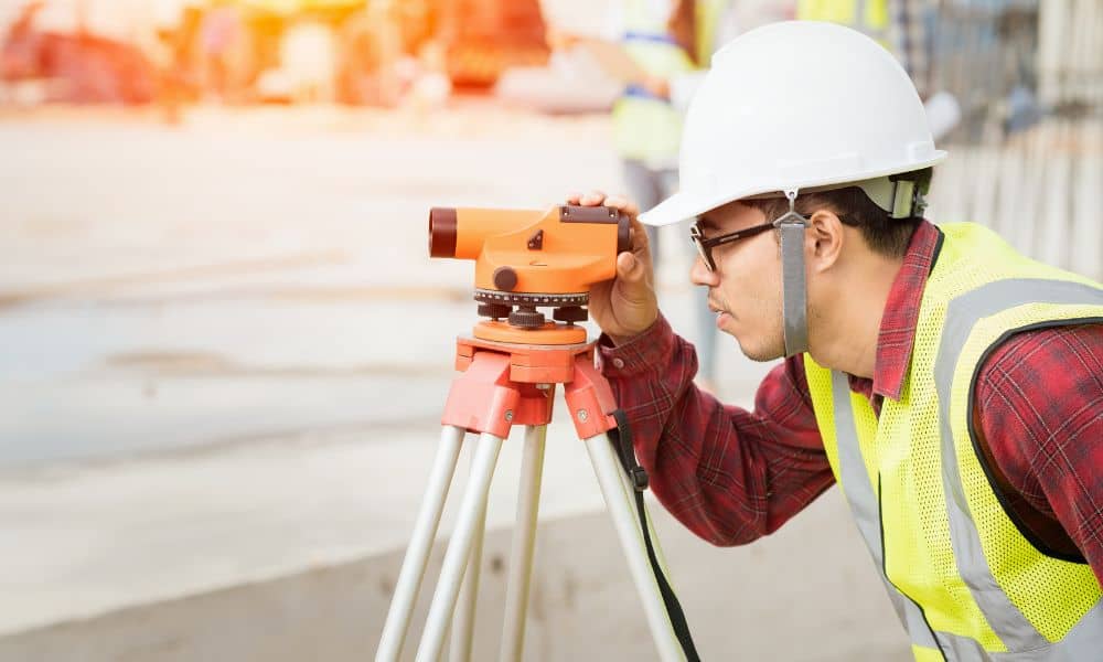 Surveyor measuring property boundaries during an ALTA land survey before a real estate purchase