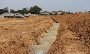 Residential development site showing utility trenches and layout markers for construction staking