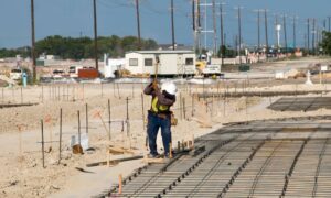 Surveyor checking construction staking on a graded site for road and building pad work