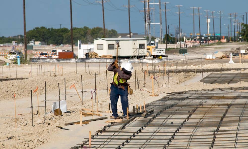 Surveyor checking construction staking on a graded site for road and building pad work
