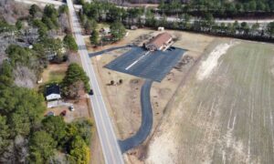 Aerial view of a commercial property with a building, parking area, access road, and open land when documenting ALTA survey utilities